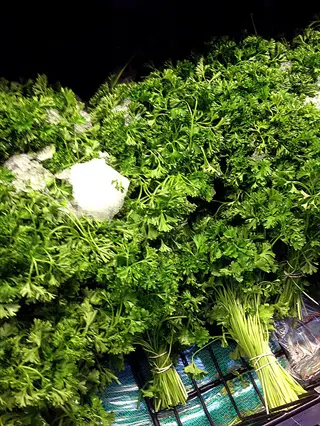 fresh bunches of curly parsley plant on a market display