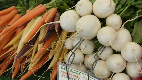 white beets garden vegetables with carrots and leafy greens at a market stall